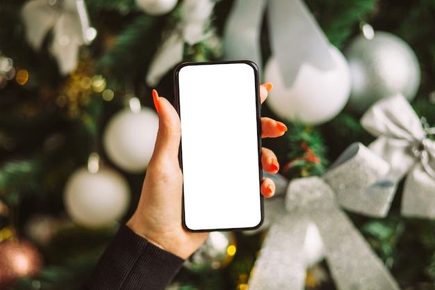 Female hand holding smartphone with blank white screen