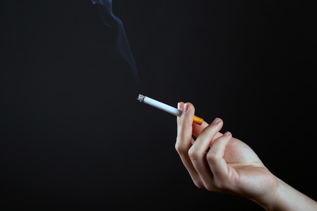 Female hand holding a smoking cigarettecopy space. harm from smoking cigarettes.