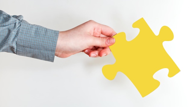 Female hand holding yellow puzzle piece