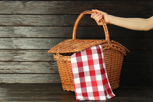 Female hand holds basket for picnic on wooden background