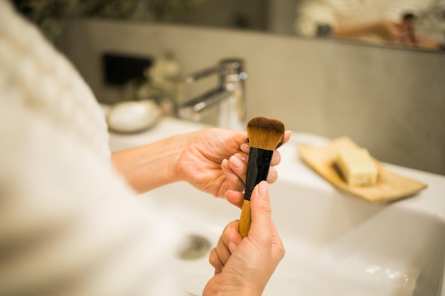 Female hand holds makeup brush in bathroom Makeup artist profession concept Variety of visagist tools glamor accessory