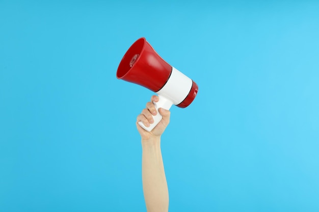 Female hand holds megaphone on blue background