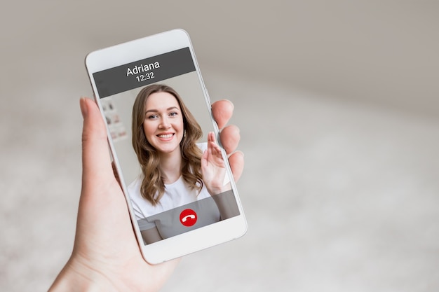 A female hand holds a mobile phone with a girl on the screen, video chat. A woman makes a video call to her friend. Happy young girl smiles on a phone screen, interface, call buttons