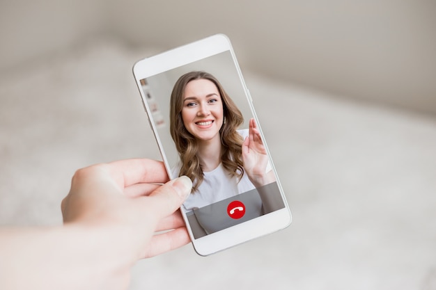 A female hand holds a mobile phone with a girl on the screen