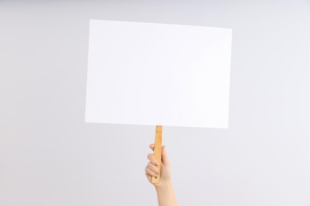 Female hand holds protest sign on light background