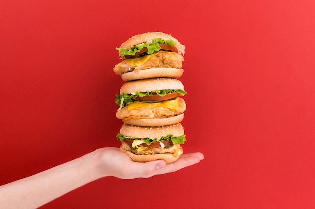 Female hand holds a pyramid of three burgers 