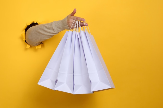 Female hand holds a white paper disposable bag with handles for groceries and clothes. Recyclable packaging. Zero waste. Sale