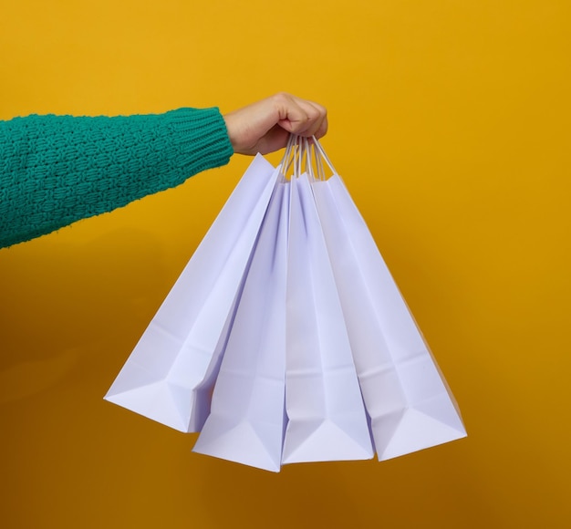 Female hand holds a white paper disposable bag with handles for groceries and clothes Recyclable packaging Zero waste Sale