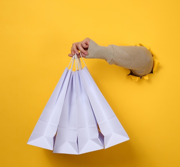 Female hand holds a white paper disposable bag with handles for groceries and clothes Recyclable packaging Zero waste Sale