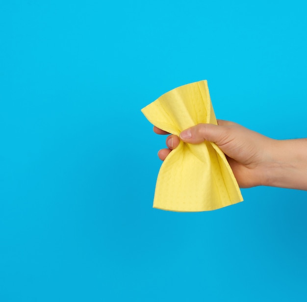 Female hand holds a yellow rag sponge for cleaning