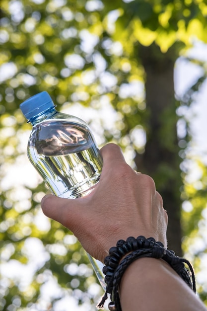 Female hand is holding a bottle with cool drinking water on a hot day