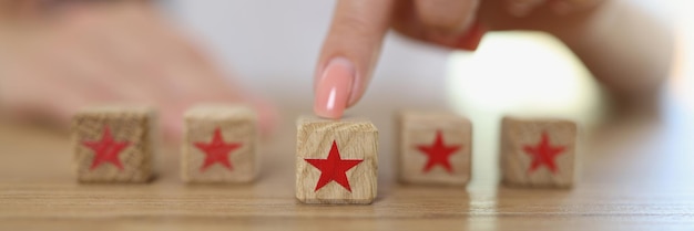 Female hand moving wooden cube with star symbol on table giving feedback response and rating