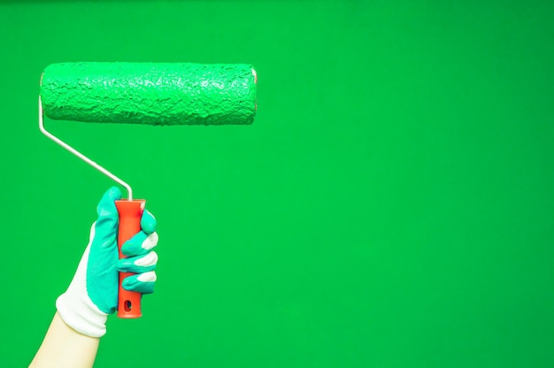 Female hand paints wall with paint roller