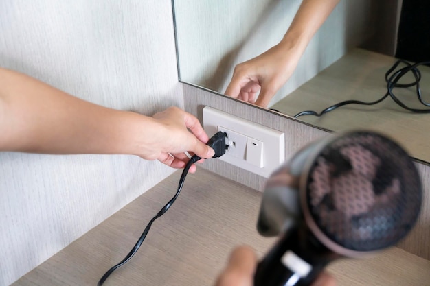 Female hand plugging in hair dryer