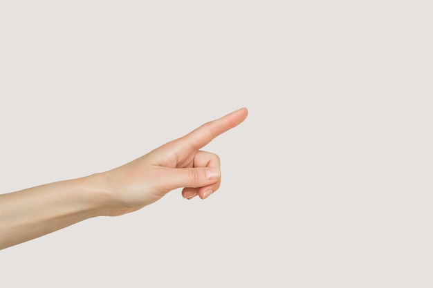 female hand pointing to empty space isolated on gray background