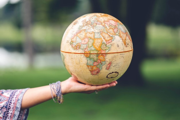 Female hand presenting a vintage globe in the blurred background travel and explore the world