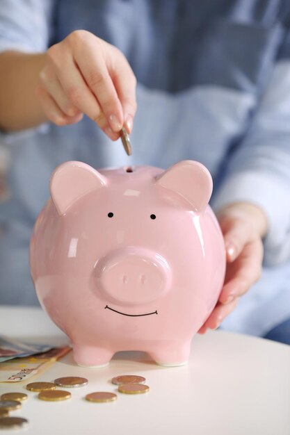 Female hand putting coin into piggy bank