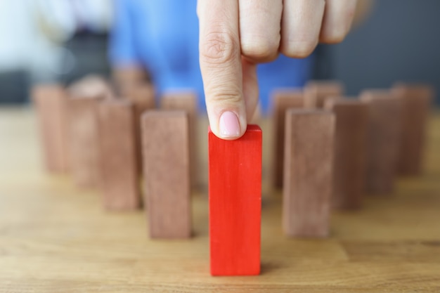 Female hand selects red wooden block among brown ones best business ideas concept