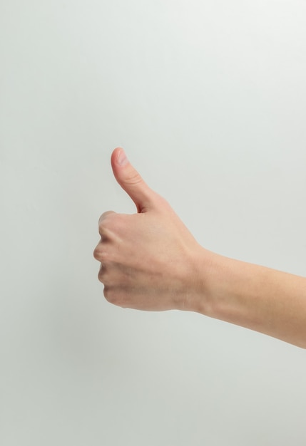 Female hand shows thumb up gesture on a white background