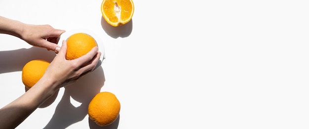 Female hand squeezes juice from oranges in a hand bowl on a white background Top view flat lay Banner