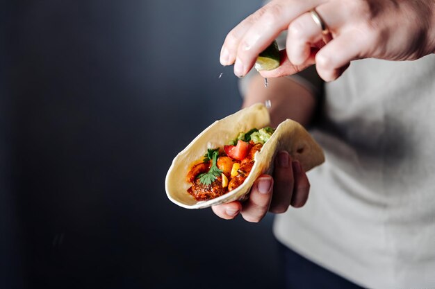 Photo female hand squeezing lime into vegan tacos