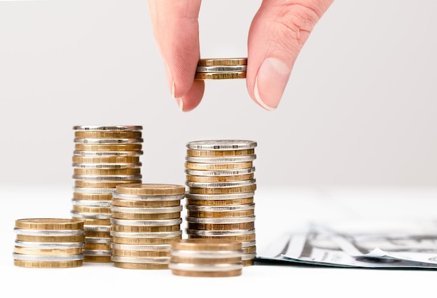 Female hand stacks coins in piles counting savings