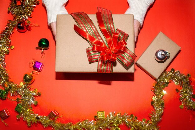 female hand in sweater holding a red present box for Christmas