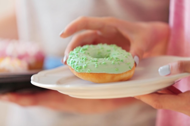 Female hand taking tasty donut from plate close up view