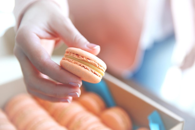 Female hand taking tasty macaroon from the box