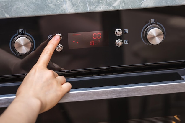 Female hand turning on the oven to make a cake at home closeup of the oven knob view of the black el