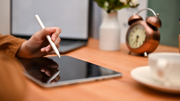 Female hand using a stylus pen with a digital tablet touchpad at her workspace