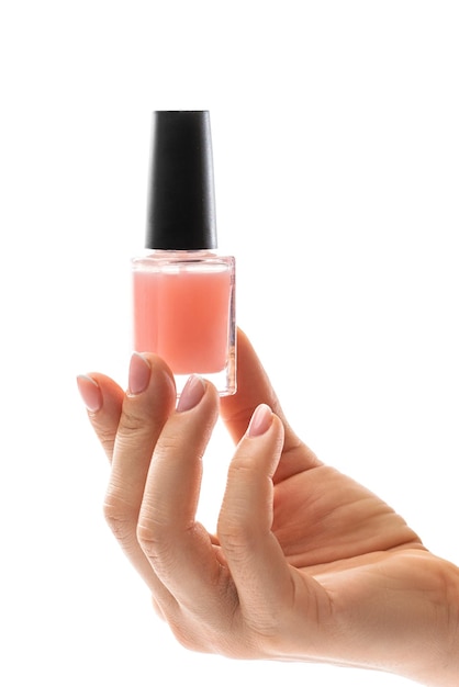 Female hand with beautiful french manicure holding bottle of pink nail polish against white background