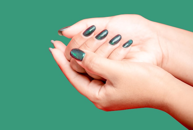 Female hand with green nail design on green background Woman manicure is art beautiful summer style Closeup of healthy young girl beauty fingers