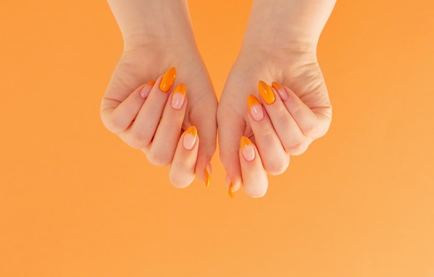 Female hand with manicure on orange background