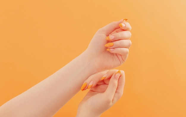 Female hand with manicure on orange background