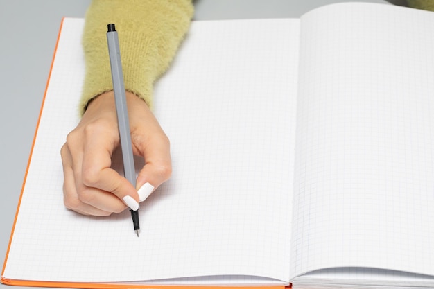 Female hand with a marker who writes on an empty notebook page