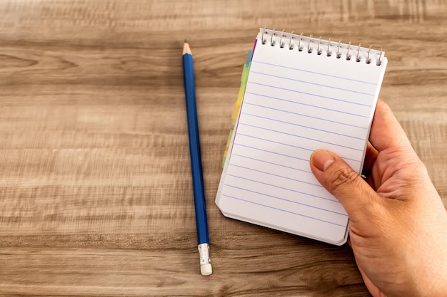 Female hand with notebook on wooden desk Business education and people concept