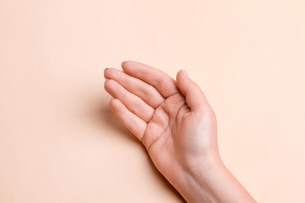 Female hand with palm up on beige background