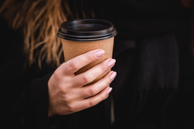 Female hand with paper cup of coffee take away