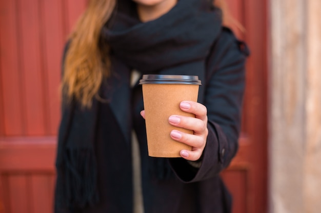 Female hand with paper cup of coffee take away 