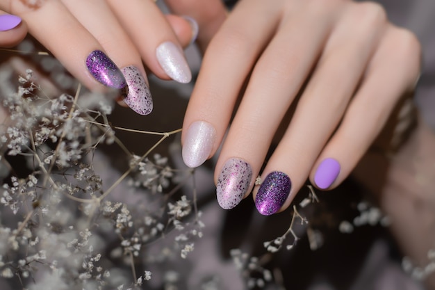 Female hand with pearly nail design with white dried flower.