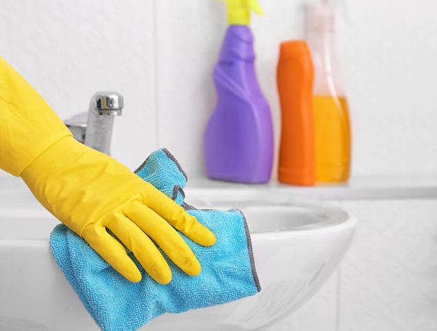 Female hand with rag cleaning a sink in the bathroom