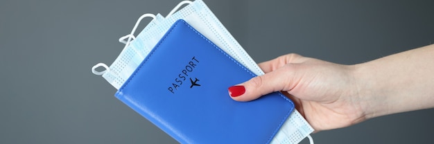 Photo female hand with red manicure holding passport and protective medical masks closeup traveling