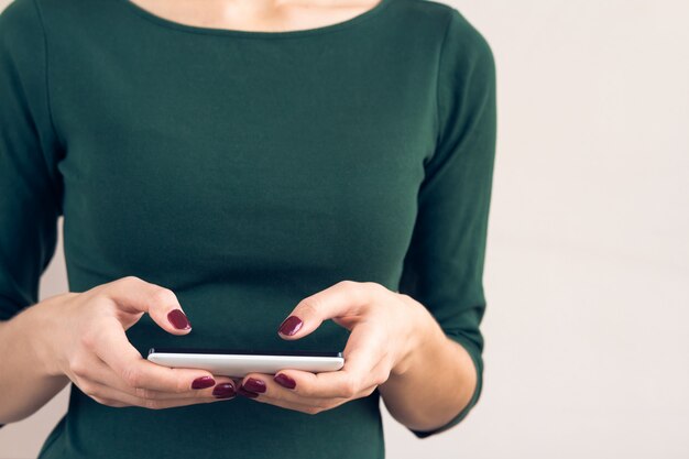 Female hand with red manicure holding white mobile phone