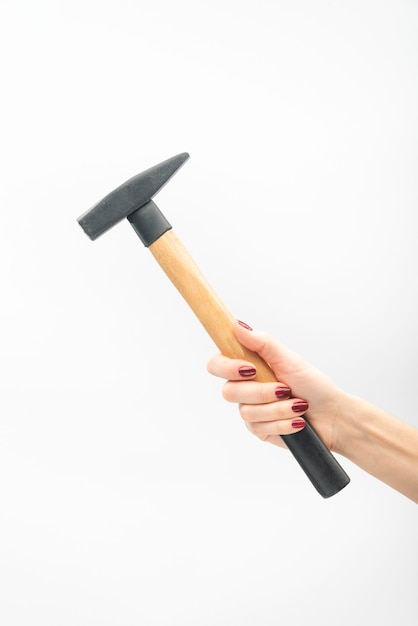 Female hand with red manicure holds hammer