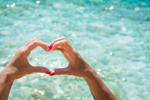 Female hand with red nail in shape of heart Love concept