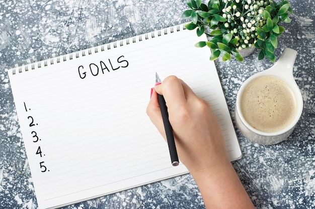 Female hand writes goals in a notebook, a planning concept