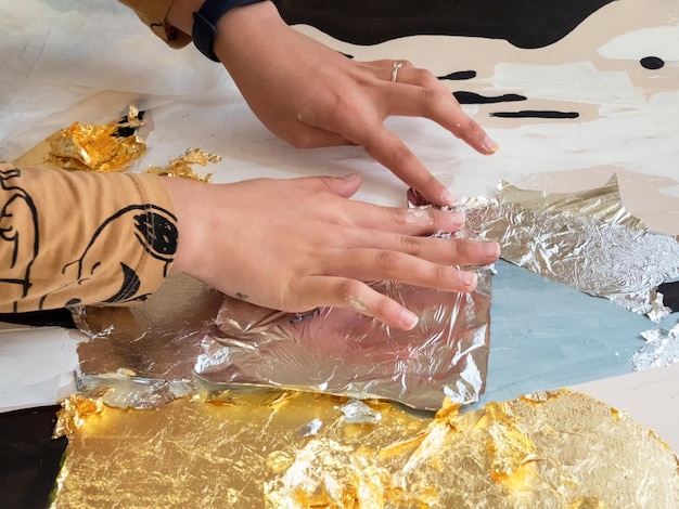 Female hands apply gold and silver potal to the picture Potal painting technique applying gold leaf particles to an interior painting