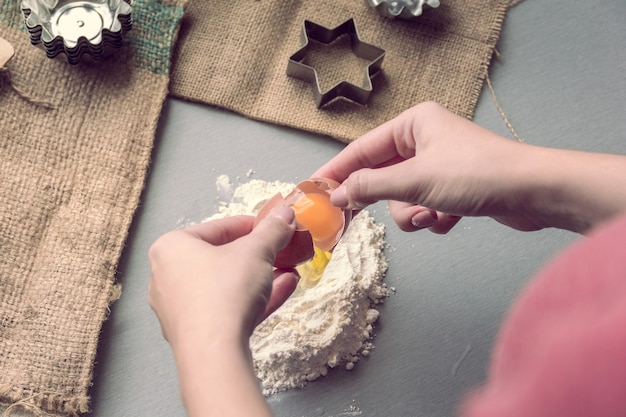 Female hands break a chicken egg into flour