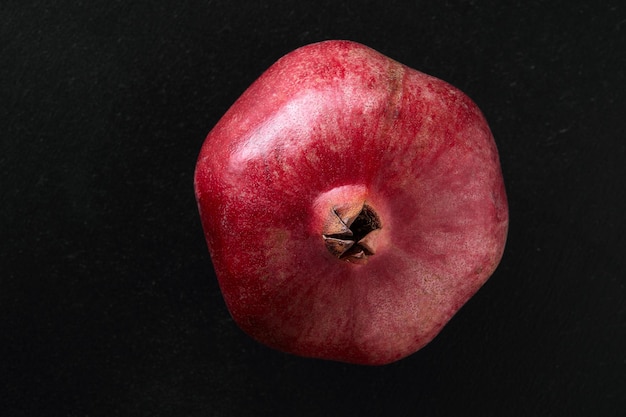 female hands breaking pomegranate in half on black background